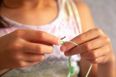 Tığ işi süreci. El ve örgü ipliği kullanan genç bir kız, el yapımı tığ işi, evde dinlenmek için hobi. Parmaklarına odaklan. Yatay resim.