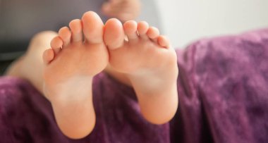 Güzel esmer kızı dijital tablet okuyarak kapatır, başvurusunda televizyon dizisi izler, oturma odasında otururdu. Çıplak ayaklara odaklan. Boşluğu kopyala.