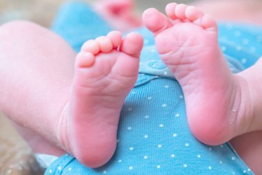 Kahverengi çarşafların üzerinde uyuyan mutlu bir bebeğin komik görüntüsü. Yeni doğmuş bir bebeğin yumuşak ayaklarını kapat. 