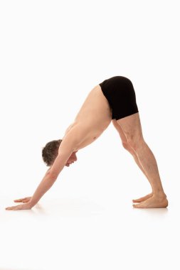 Adho Mukha Svanasana, Ashtanga yogası spor giysili bir adamın beyaz arka planda yoga yaparken görüntüsü. 