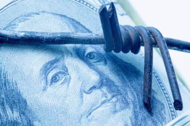 Ekonomik çatışma ve savaş, yaptırımlar ve ambargo kırma kavramı. Amerikan Doları 'na karşı dikenli tel. Benjamin Franklin 'in gözlerine odaklan. Yatay resim.