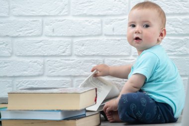 Küçük bebek kitaplara bakıyor. Yeni doğanların entellektüel gelişimi. Metin veya tasarım için boşluk kopyala.