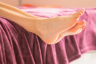 Genç bir kadın çıplak ayakla evde yatıyordu. Yatay resim.