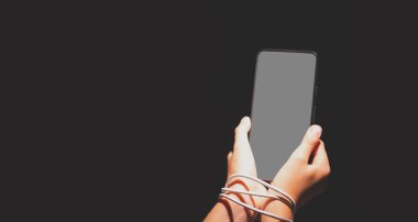 Bilgisayar, medya, oyun, ağ, dijital, teknoloji, cihaz ve internet bağımlılığı. Geceleri akıllı telefon kullanan elleri bağlı genç ve güzel bir kız. Boşluğu kopyala.