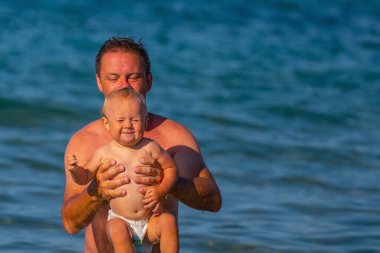 Baba, bebekle birlikte denizde yüzüyor. Doğa, seyahat, okyanusta oynayan mutlu baba ve çocuk. Boşluğu kopyala.