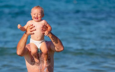 Çocukların mutluluğu, güvenliği, bağlılığı, psikolojik sağlık konsepti. Okyanusta oynayan çocuklu mutlu bir baba. Boşluğu kopyala.