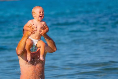 Baba portresi denizde bebekle birlikte yüzüyor. Doğa, seyahat, okyanusta oynayan mutlu baba ve çocuk. Metin veya tasarım için boşluk kopyala.