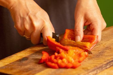 İtalyan ekmeği ve malzemeleri - parmesan, zeytinyağı, domates, baharat ve bitkiler. Şefin ellerinin portresi pizzada kırmızı biber dilimleri keser. Seçici odaklanma. Yatay resim.