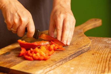 İtalyan ekmeği ve malzemeleri - parmesan, zeytinyağı, domates, baharat ve bitkiler. Şefin ellerini kapayın, pizzada kırmızı biber dilimleri kesin. Seçici odaklanma. Yatay resim.