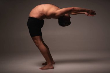 Ashtanga yogası. Spor giysili bir adamın karanlık arka planda yoga yaparken görüntüsü.. 