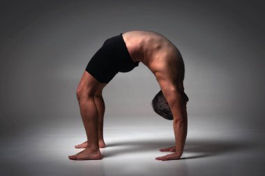 Parivrtta Asana B, Ashtanga yogası spor giysili bir adamın karanlık arka planda yoga yaparken görüntüsü.. 