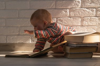 Çocuk gelişimi ve erken öğrenme kavramı. Kitaplı küçük bir bebeğin komik portresi. Yeni doğanların entelektüel gelişimi. 