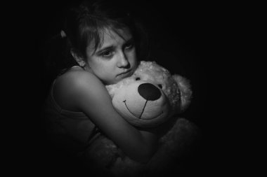 Yalnız küçük kız oyuncağının portresi, evde yalnız başına oturuyor, mutsuz çocuk ailesini bekliyor, sorunları düşünüyor, ailedeki kötü ilişki, psikolojik travma. Yatay resim.