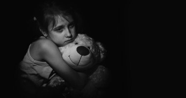 Yalnız küçük kız oyuncağının portresi, evde yalnız başına oturuyor, mutsuz çocuk ailesini bekliyor, sorunları düşünüyor, ailedeki kötü ilişki, psikolojik travma. Boşluğu kopyala.