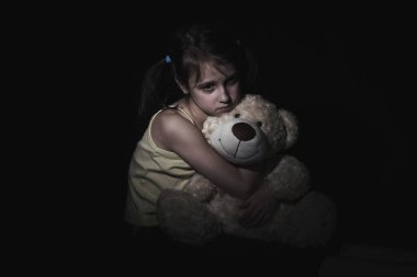 Yalnız küçük kız oyuncağını kucaklıyor, evde tek başına oturuyor, üzgün çocuk ailesini bekliyor, sorunları düşünüyor, ailedeki kötü ilişki, psikolojik travma