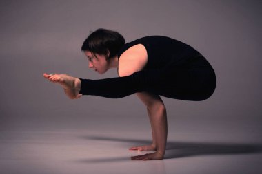 Tittibhasana, Ashtanga yogası kadın spor kıyafetleri giyip karanlık arka planda yoga yapıyor.. 