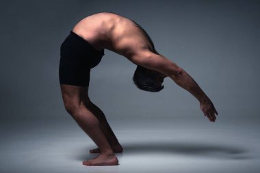 Ashtanga yogası. Spor giysili bir adamın karanlık arka planda yoga yaparken görüntüsü.. 