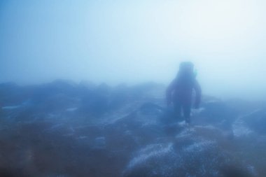 Dünyanın bir ucundayım. Dağlardaki bulutlar ve sisli bir dağın tepesindeki dağcı silueti. Boşluğu kopyala.