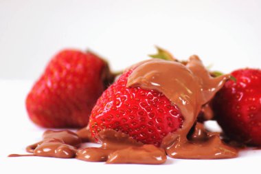 Çilekleri çikolatayla kaplayıp beyaz arka plana koyun. Yatay resim. 