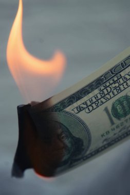 Uluslararası gümrük vergilerine yapılan zamlar, düşen borsa ve küresel ekonomik krizin bir simgesi olarak yakılan Amerikan dolarlarının yakın plan fotoğrafları. Dikey resim.