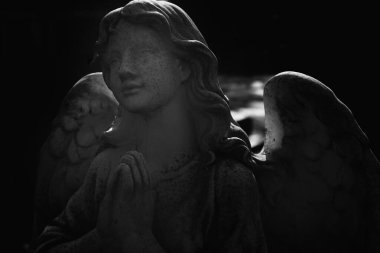 Çarmıhlı üzgün melek. Ağza alınmayacak bir üzüntü ve ölümün sembolü olarak görünen tatlı bir ifadeyle antik taş heykel parçası. Siyah ve beyaz.