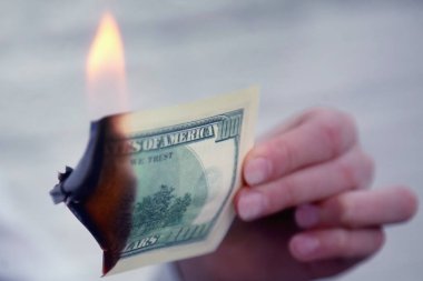 Uluslararası gümrük vergilerine yapılan zamlar, düşen borsa ve küresel mali krizin bir simgesi olarak yakılan ABD Doları banknotları. Kapat..