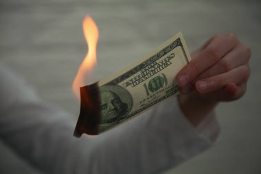 Uluslararası gümrük vergilerine yapılan zamlar, düşen borsa ve küresel ekonomik krizin bir simgesi olarak yakılan Amerikan dolarlarının yakın plan fotoğrafları. Yatay resim.