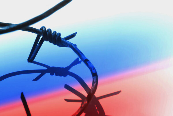 Колючая проволока против российского флага как символ тоталитаризма и авторитаризма русского. Пространство для копирования дизайна. Горизонтальное изображение.