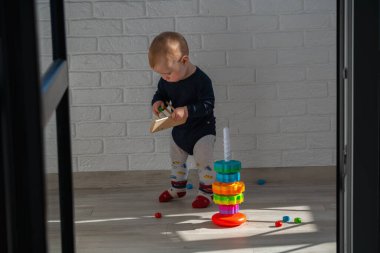 Küçük bebek tahta oyuncaklarla oynamaya başladı. Çocuk bir tasnif makinesi topluyor. Çocuklar için eğitici mantık oyuncakları. Bebek oyun zamanı..