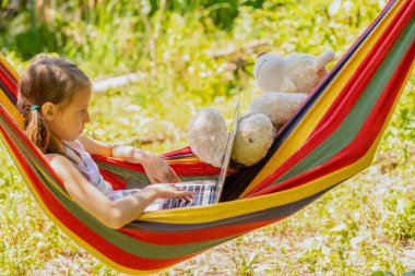 Hamakta dinlenirken dizüstü bilgisayar kullanan başarılı kadın serbest çalışanın portresi. Ücretsiz, uzak ve uzak iş konsepti.