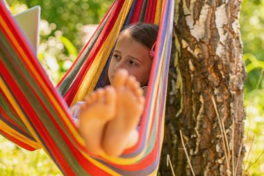 Hamakta dizüstü bilgisayarla yatan güzel bir kız.