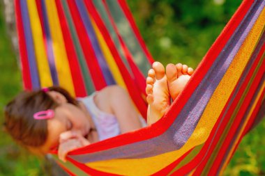 Genç güzel kız yeşil bahçedeki hamakta dinleniyor ve uyuyor.