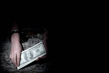 Para bağımlılığı. Genç bir kız, bir kişinin paraya olan bağımlılığının bir sembolü olarak elleri kelepçeli olarak parayı elinde tutuyor..