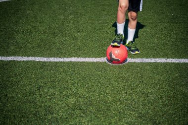 Kırmızı futbol forması giyen, futbol oynayan, sahada, dışarıda futbol oynayan tatlı bir çocuk. Aktif çocuk, gülümseyen mutlu çocuk yazın eğleniyor..