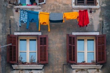 Çamaşırlar renkli cephelerde asılı, Rovinj 'deki antik Akdeniz binaları, Hırvat kıyısındaki eski kasaba. Eski Venedik evi duvarı ve açık havada kuruyan elbiseler..
