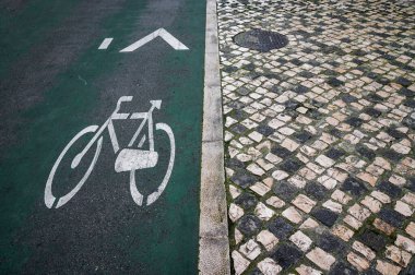 Yağmurlu bir günde bisiklet yolu. Asfalta bisiklet boyası için tabela. Klasik Lisboa Portekiz geçmişi. Bölme çizgisi, perspektif azalması, bisiklet yolunda beyaz bisiklet işareti.