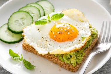Kahvaltıda kızarmış yumurtalı avokado tostu, sağlıklı yemek.