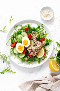 Salad with canned tuna, boiled egg, arugula and fresh vegetables. Top view