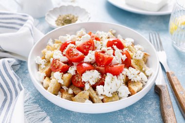 Dakos or koukouvagia salad. Classic recipe Cretan barley rusk salad with fresh tomato, mizithra cheese and oregano. Traditional mediterranean Greek cuisine. Healthy food, diet