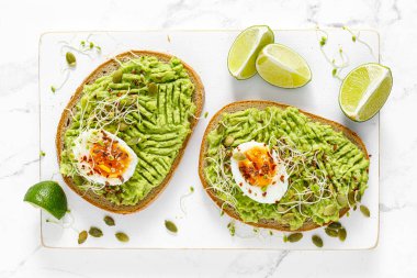 Avocado toast with boiled egg, seeds and sprouts on white background. Healthy diet food. Top view