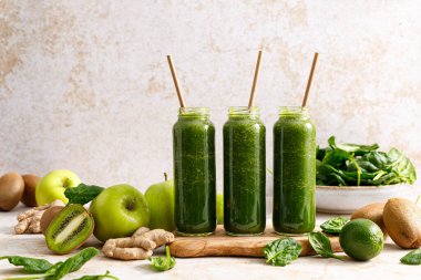 Smoothie. Healthy fresh raw detox spinach smoothie with green apple, kiwi and ginger in a bottles on a table. Healthy diet vegan food full of antioxidants