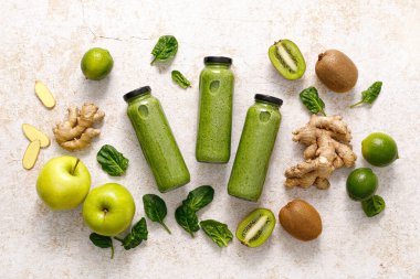 Smoothie. Healthy fresh raw detox spinach smoothie with green apple, kiwi and ginger in a bottles on a table. Healthy diet vegan food full of antioxidants