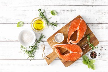 Tahtada taze çiğ somon bifteği ve yemek malzemeleri var.