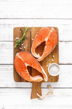 Tahtada taze çiğ somon bifteği ve yemek malzemeleri var.