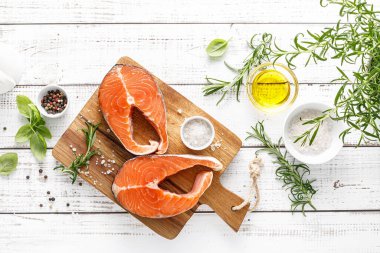 Tahtada taze çiğ somon bifteği ve yemek malzemeleri var.
