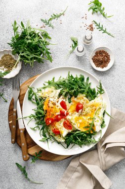 Kızarmış yumurta, soğanlı omlet, domates ve taze roka salatası.