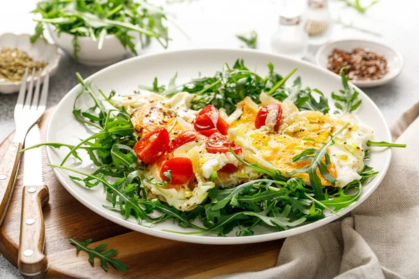 Kızarmış yumurta, soğanlı omlet, domates ve taze roka salatası.
