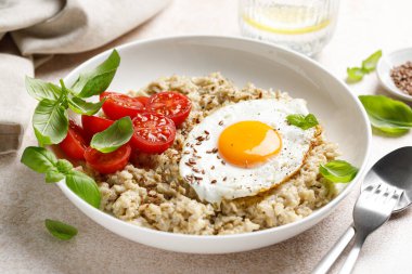 Yağda kızartılmış yulaf ezmesi, yumurta, domates ve fesleğen.