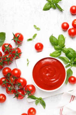 Domates ezmesi, sos, ketçap ve kiraz domatesleri dallarda ve fesleğende fotokopi alanı beyaz arkaplanda, üst görünümde.