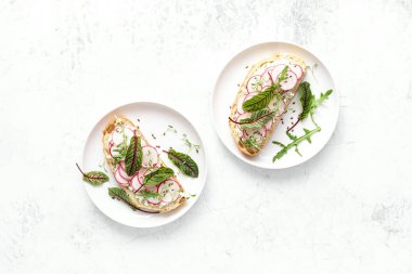 Süzme peynirli turp sandviçler ve taze yeşil yapraklar. 